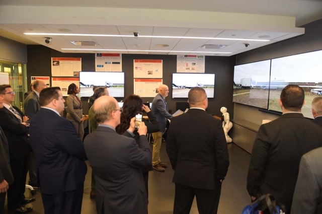 People standing around cyber security lab applauding in front of screens
